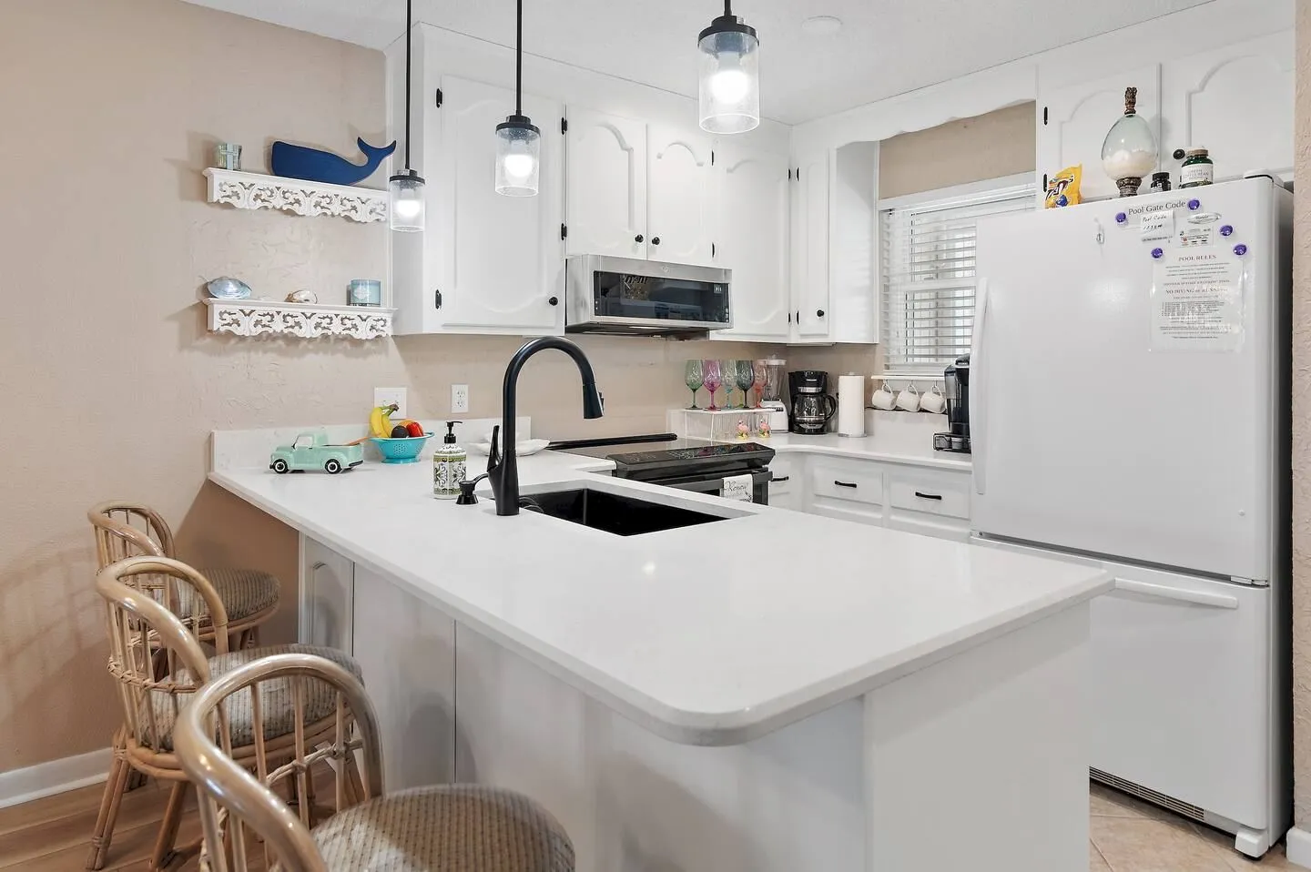 Kitchen featuring a breakfast bar with wicker barstools, white cabinetry, white countertops, and a white refrigerator.