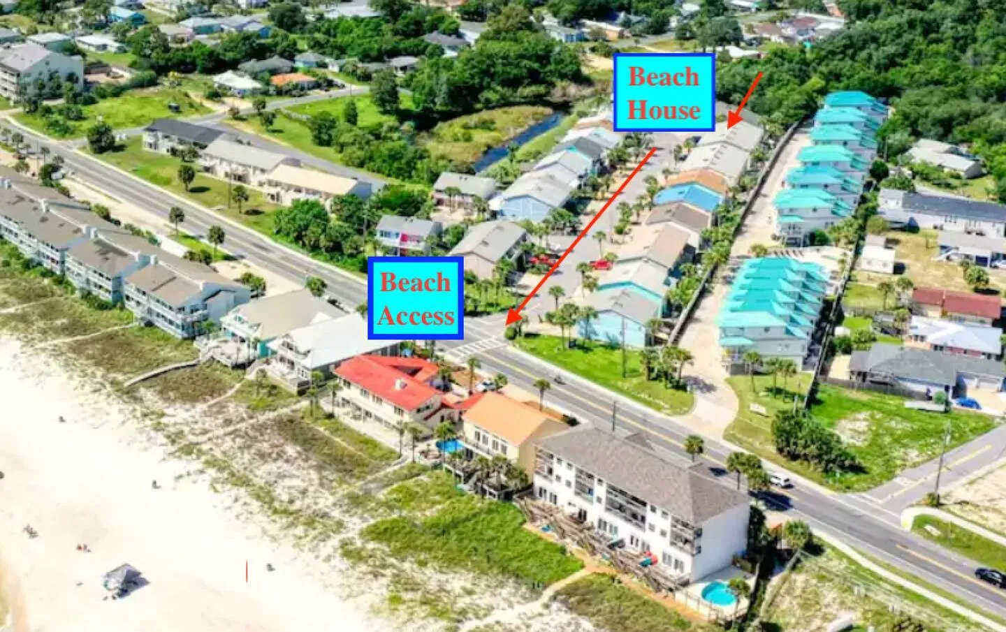 Aerial view showing the residential street, marked beach house location, crosswalk, and sandy beach.