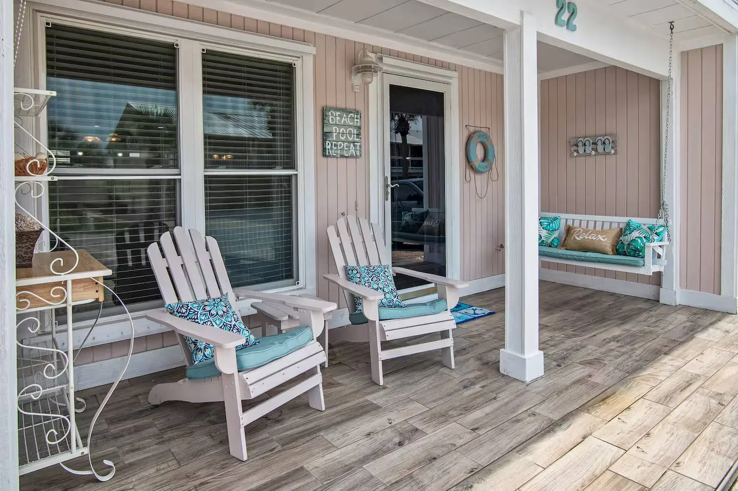 Covered front porch with wood-look tile flooring, two Adirondack chairs, and a hanging porch swing.