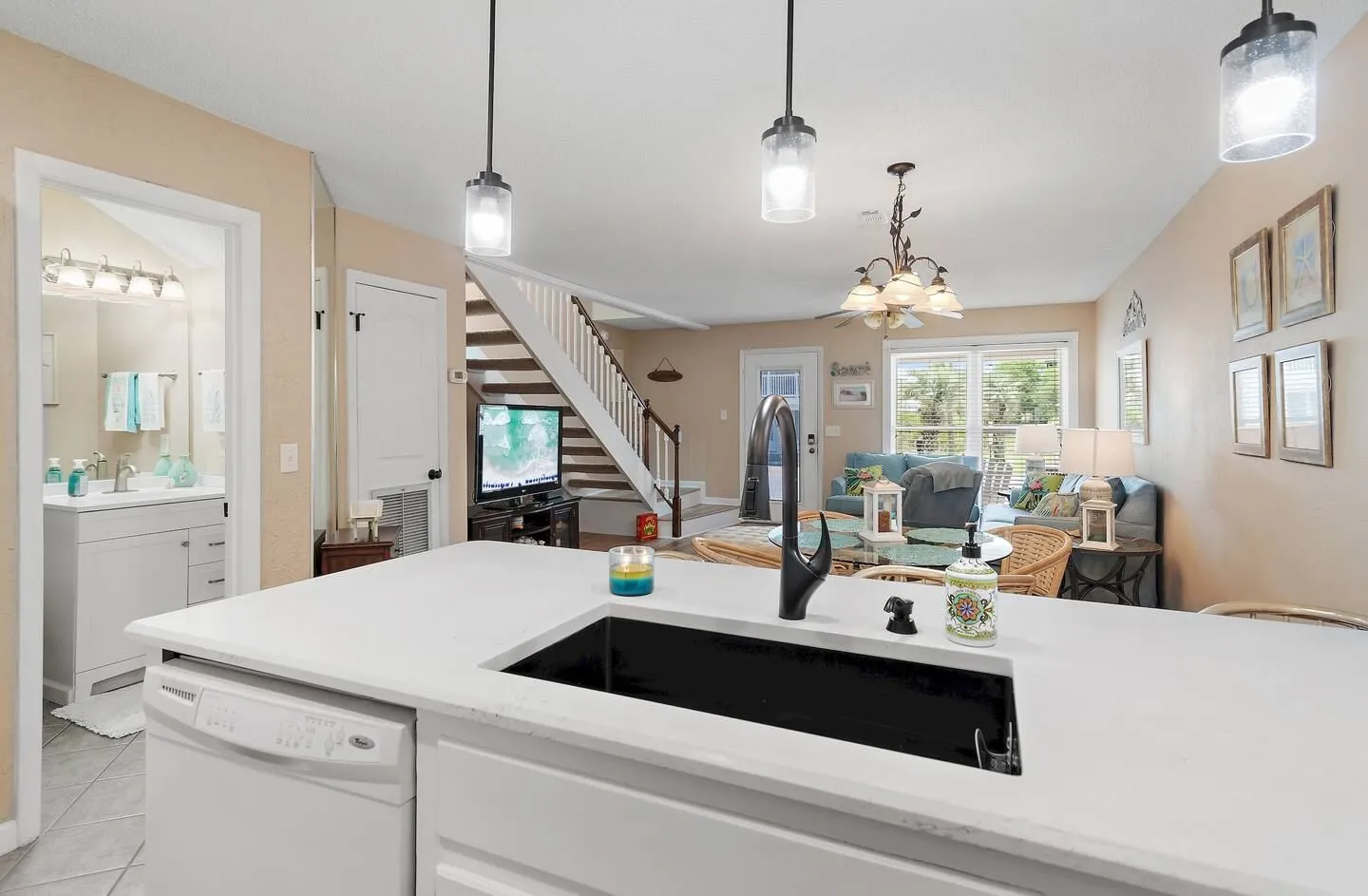 View from an open kitchen counter and undermount sink looking into the dining area and living room with stairs.
