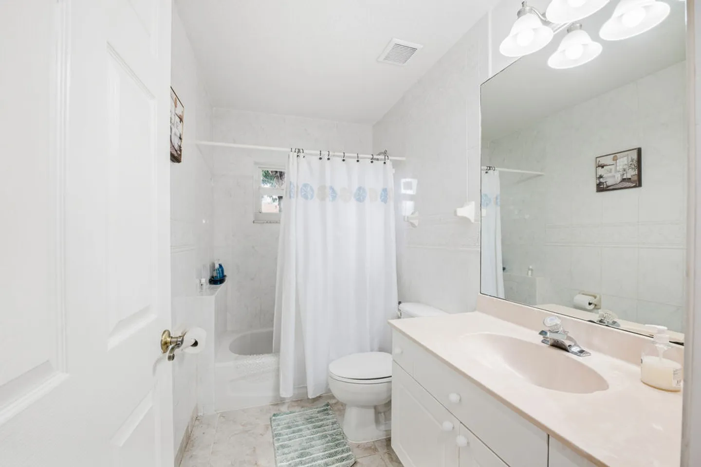 Bathroom with a white vanity, large mirror, toilet, and a bathtub with a white shower curtain.