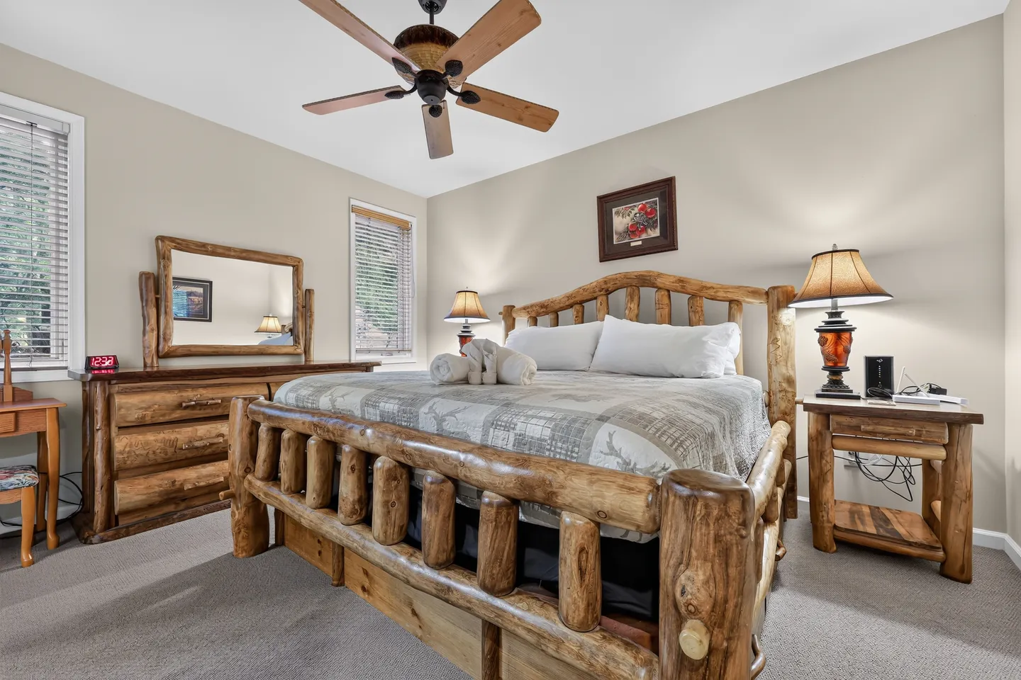 Bedroom featuring rustic log-style furniture including a bed, dresser with mirror, and nightstand, complemented by a ceiling fan.