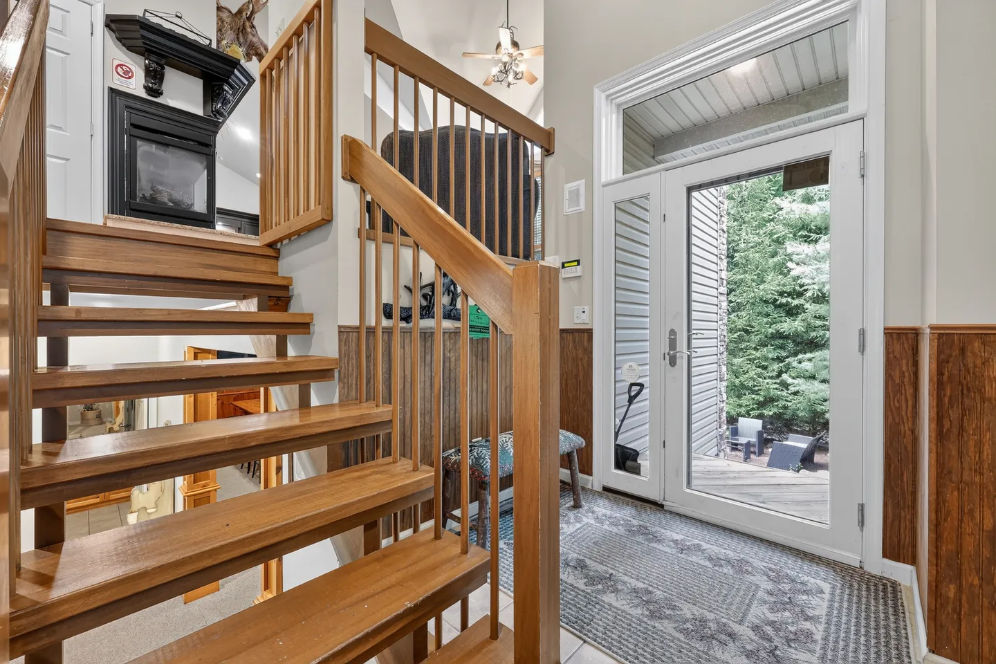 Entryway with a glass front door, transom window, and a wooden open-tread staircase leading upstairs.