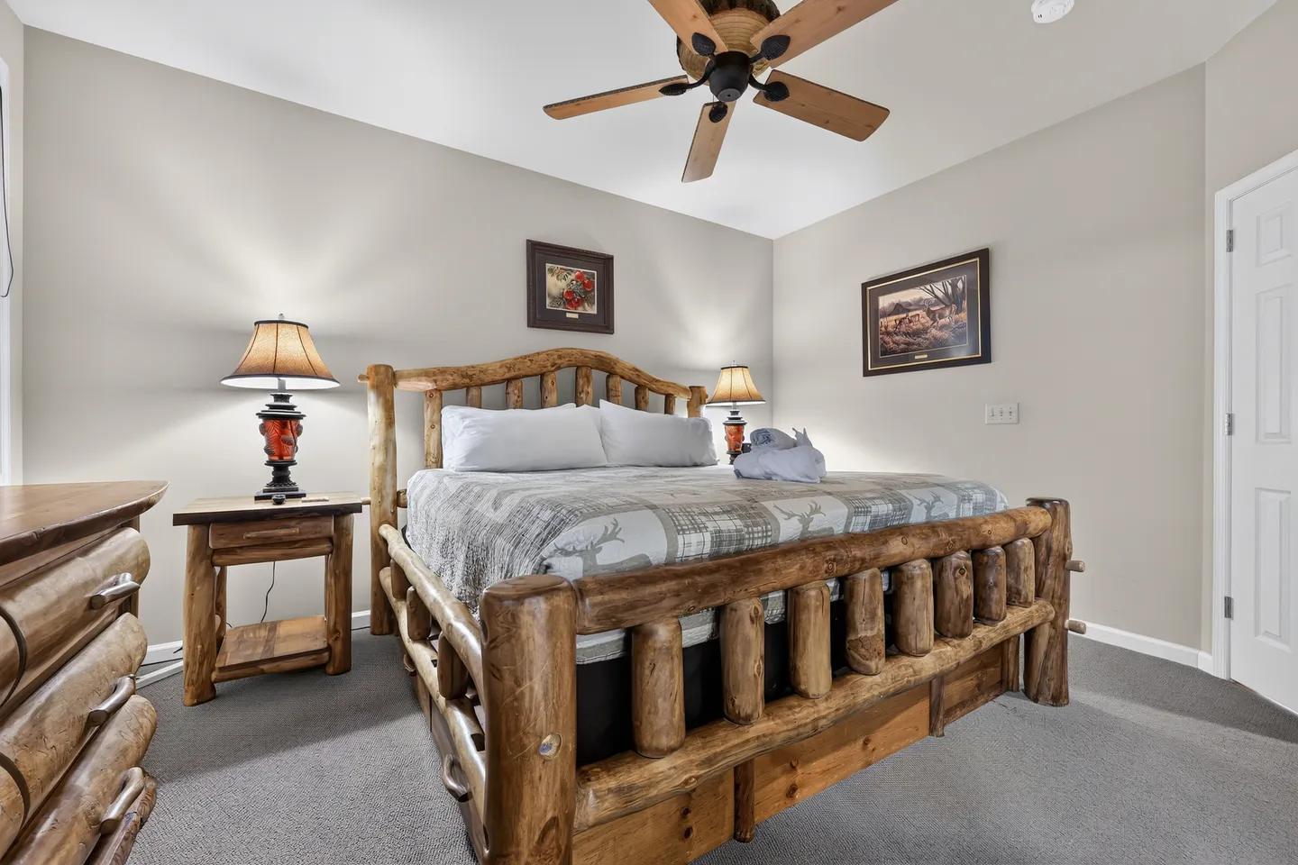 Bedroom featuring a log-style wooden bed frame, matching nightstand and dresser, and a ceiling fan.