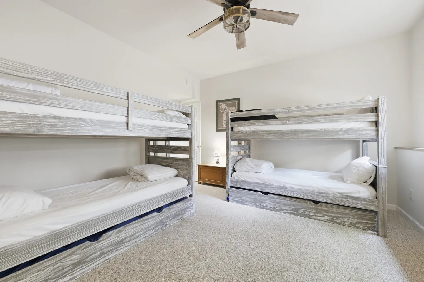 Bedroom with two light-wood bunk beds, carpeted flooring, and a ceiling fan.