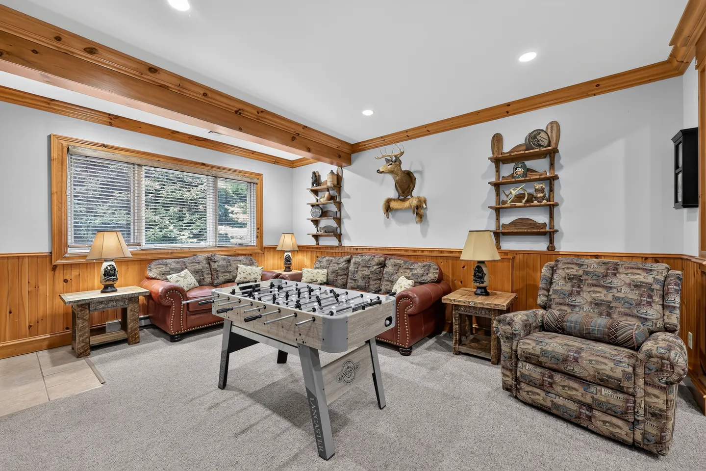 Game room featuring a foosball table, rustic armchairs and sofas, and taxidermy wall decor.