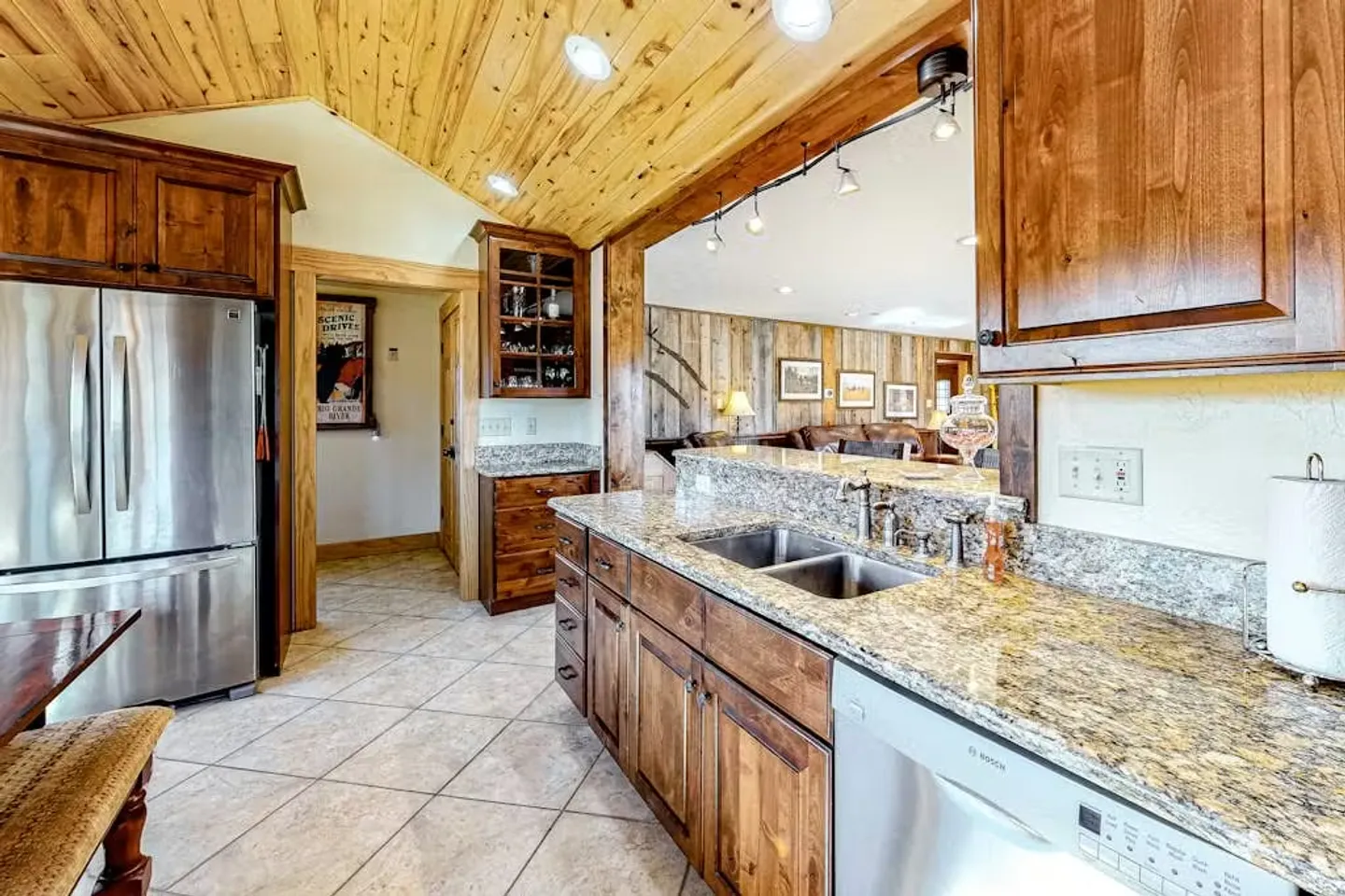 Kitchen featuring wood paneled cabinets, speckled stone countertops, stainless steel appliances, and a wood plank ceiling.