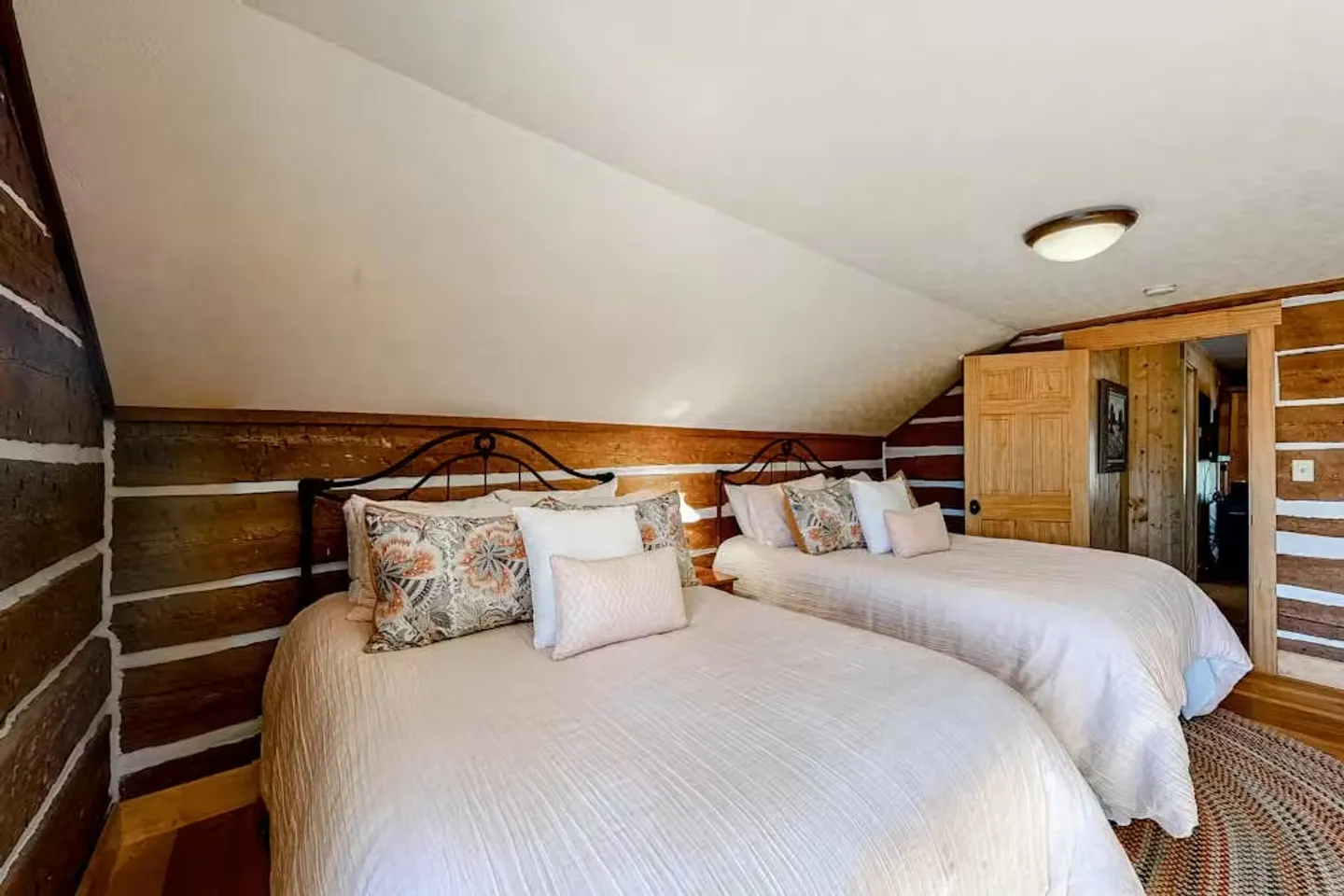 Bedroom with two beds, metal headboards, log-style walls, and a sloped ceiling.