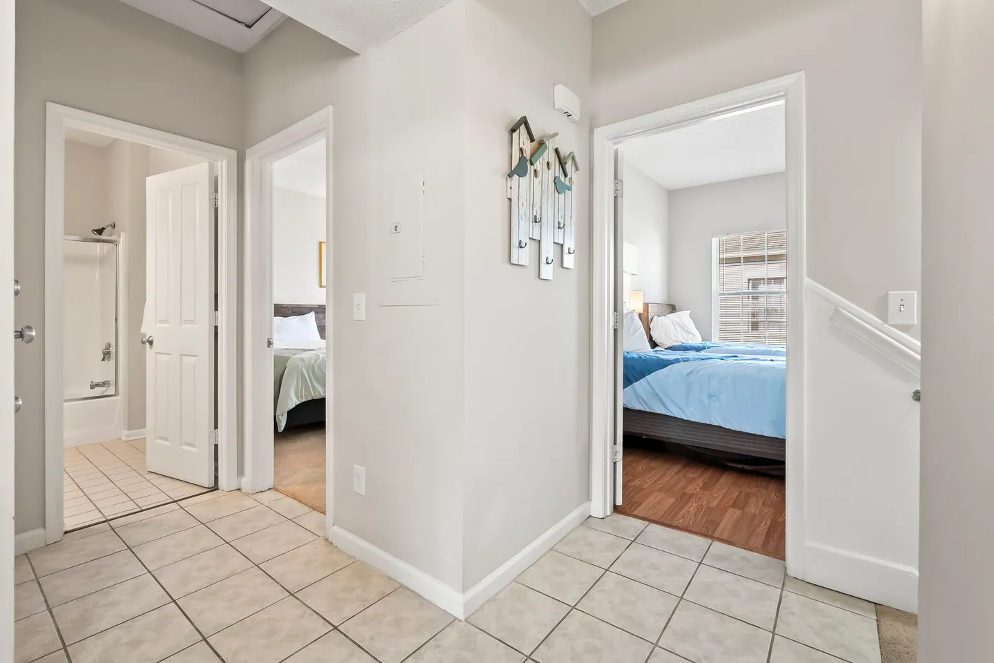 Hallway with tile flooring leading to two bedrooms and a bathroom.