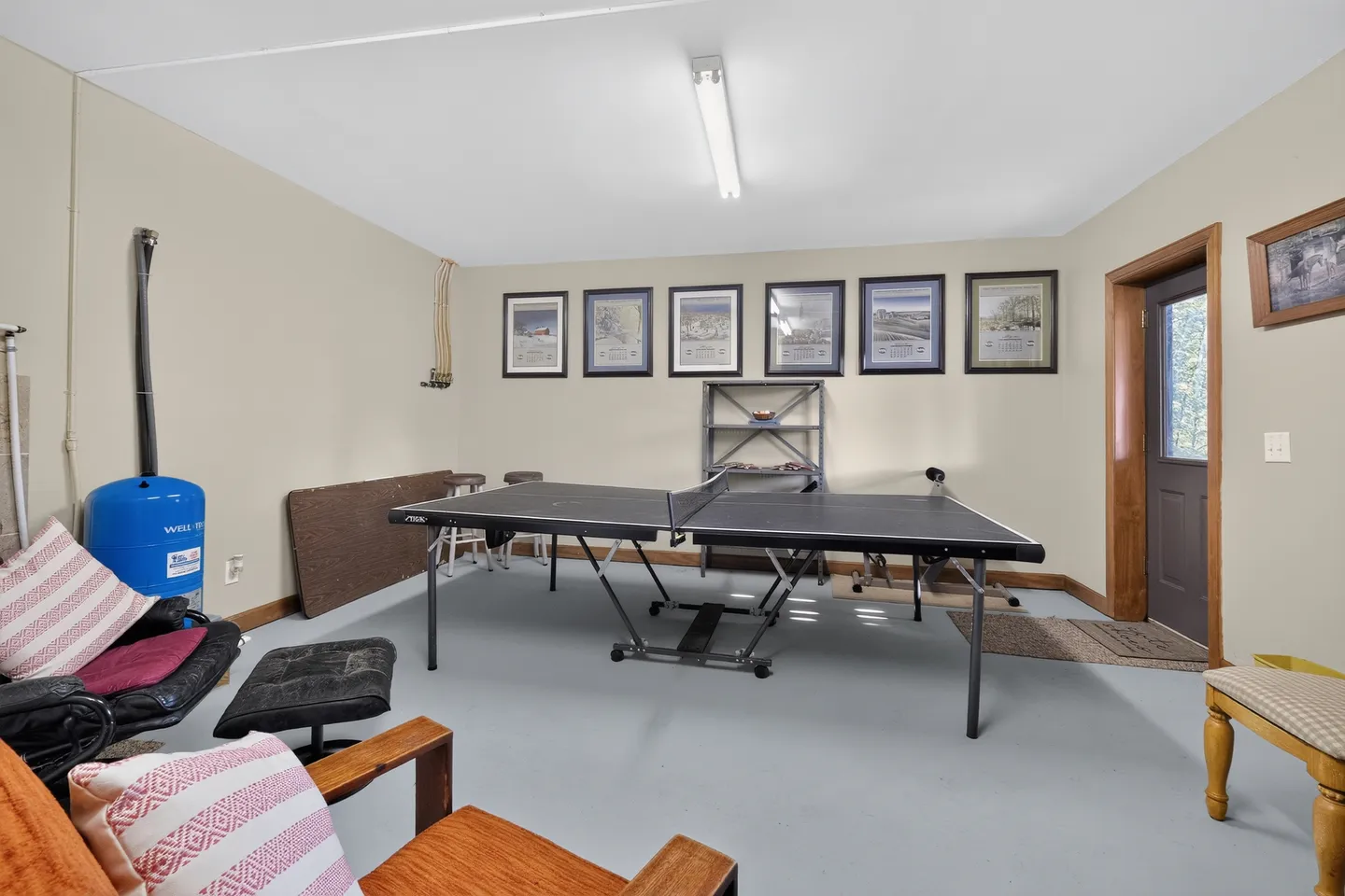Game room featuring a ping-pong table centered on a light-colored floor with seating and framed pictures on the wall.