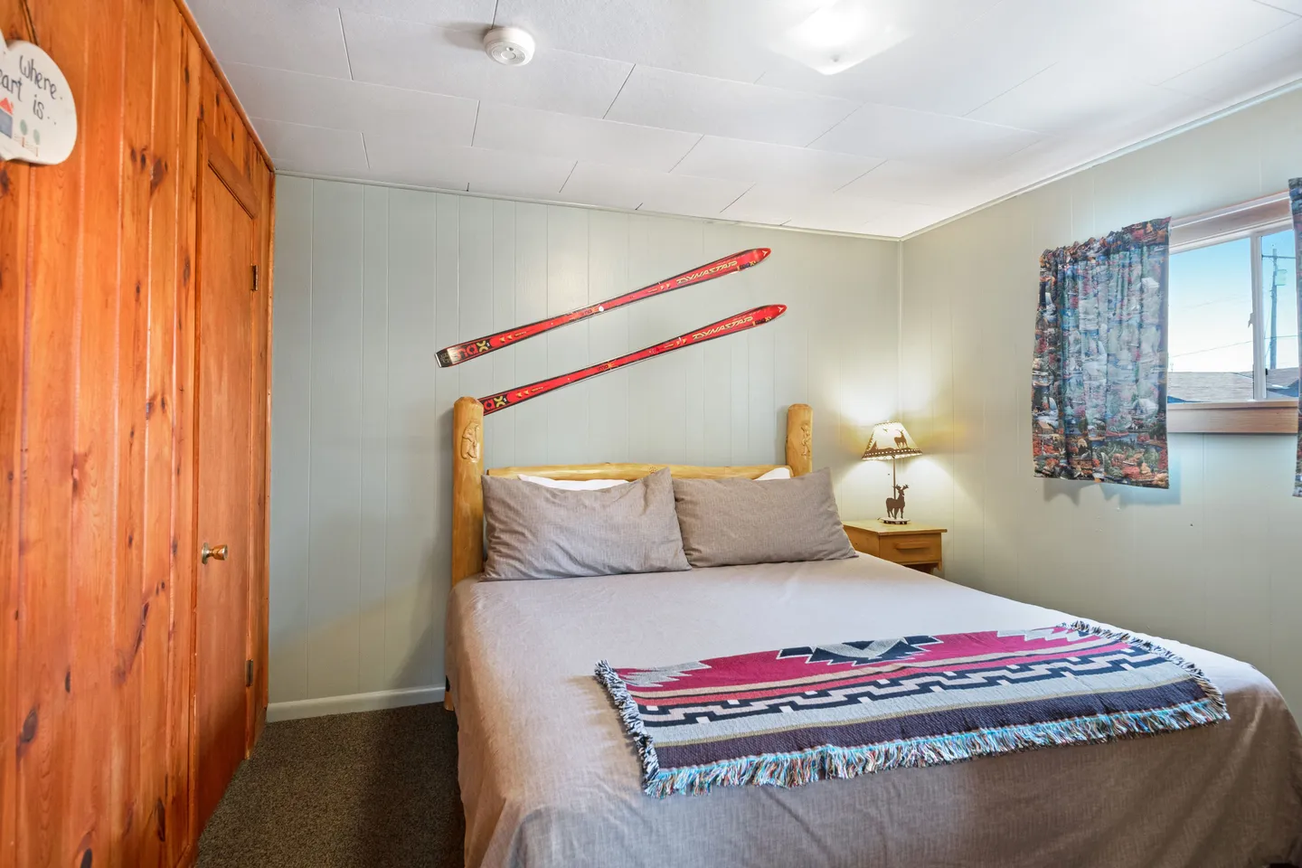 Bedroom featuring a log-style bed with red skis mounted on the wall above the headboard.