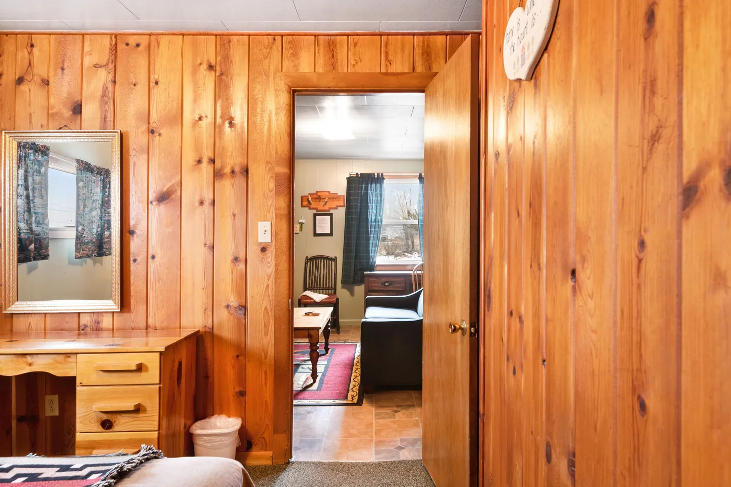 View through a wood-paneled doorway into a living area with a sofa, chair, and coffee table.