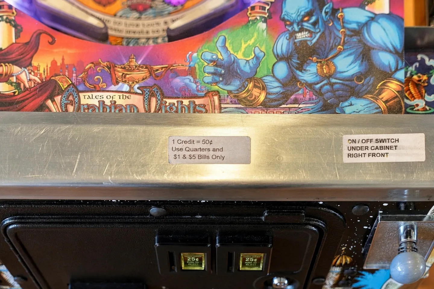 Close-up of a Tales of the Arabian Nights pinball machine front panel and coin slots.