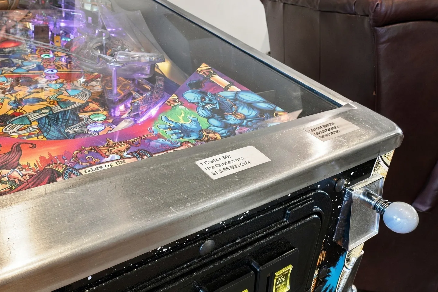 Close-up of a pinball machine showing the glass playfield, plunger, and front coin door.