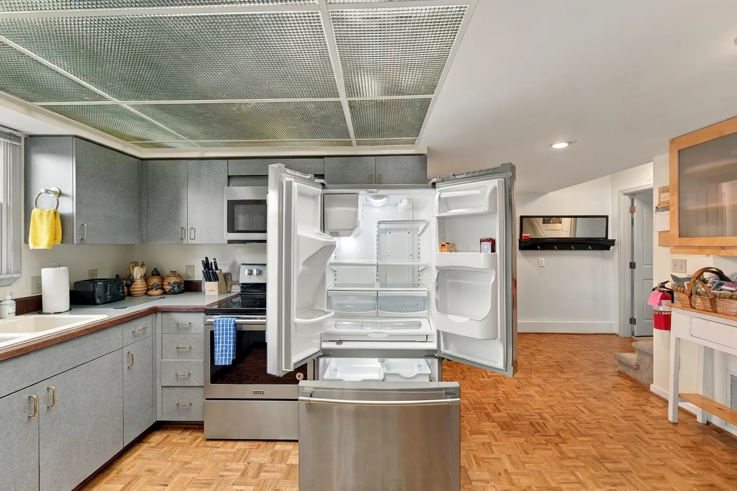 Kitchen featuring parquet flooring, grey cabinetry, stainless steel appliances, and an open French door refrigerator.