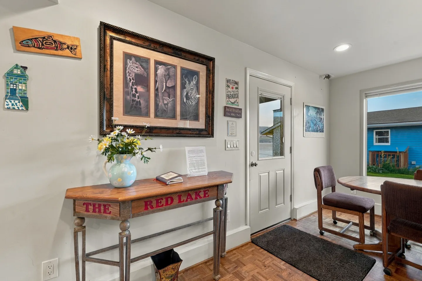 Entryway featuring parquet wood flooring, an exterior door with glass insert, a console table labeled 'The Red Lake', and framed animal art on the wall.