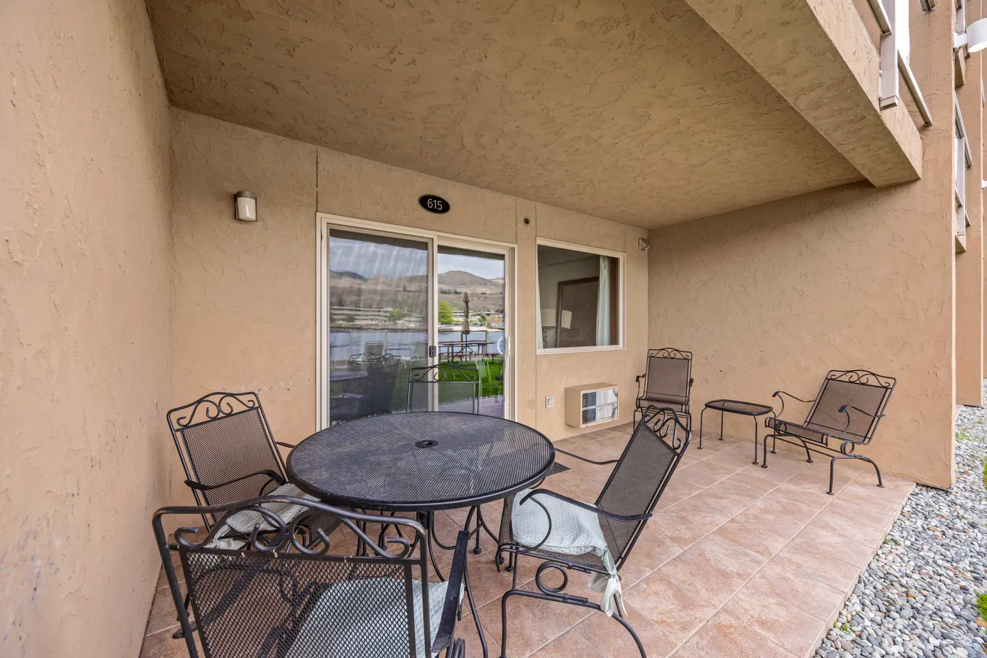 Covered outdoor patio with a tiled floor, round patio table with chairs, and sliding glass door leading inside.