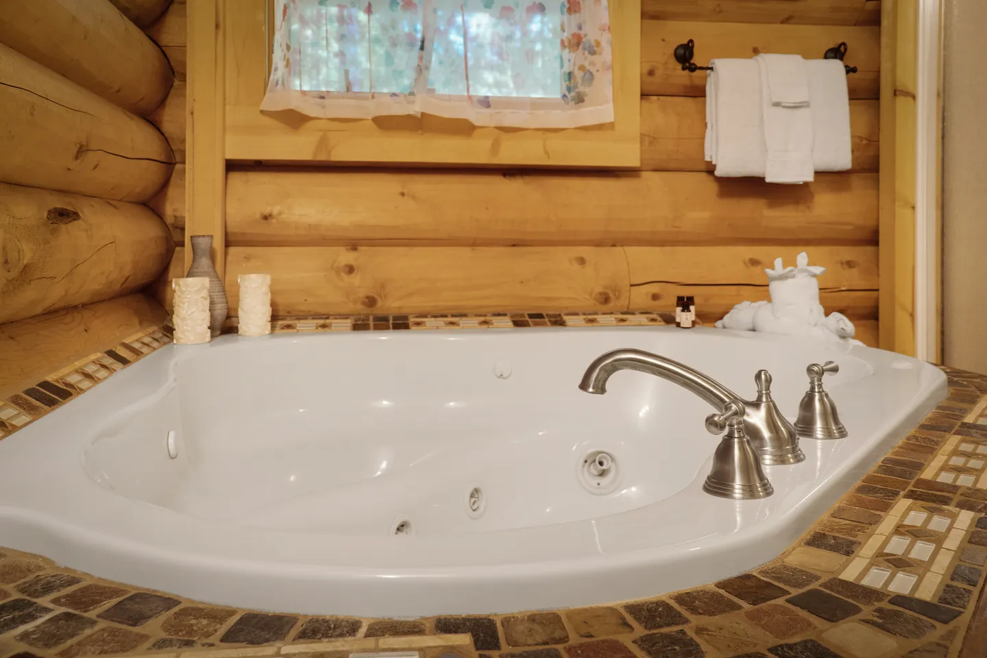 Built-in indoor jetted soaking tub set into tiled surround against log cabin walls.