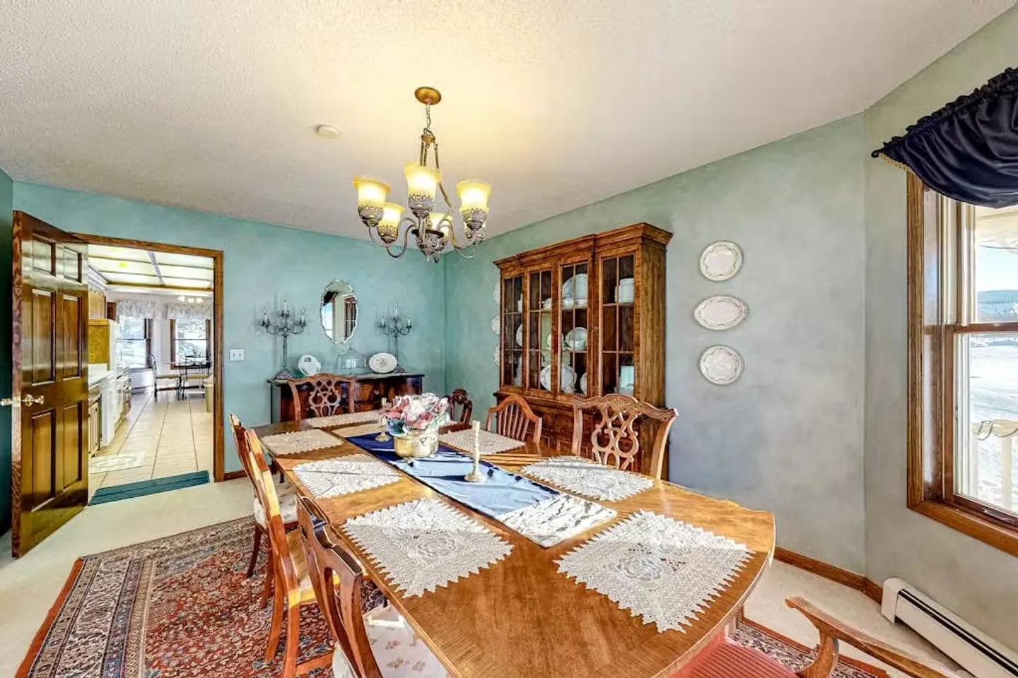 Formal dining room with a long wooden table, chairs, a glass-front china cabinet, and light blue walls.