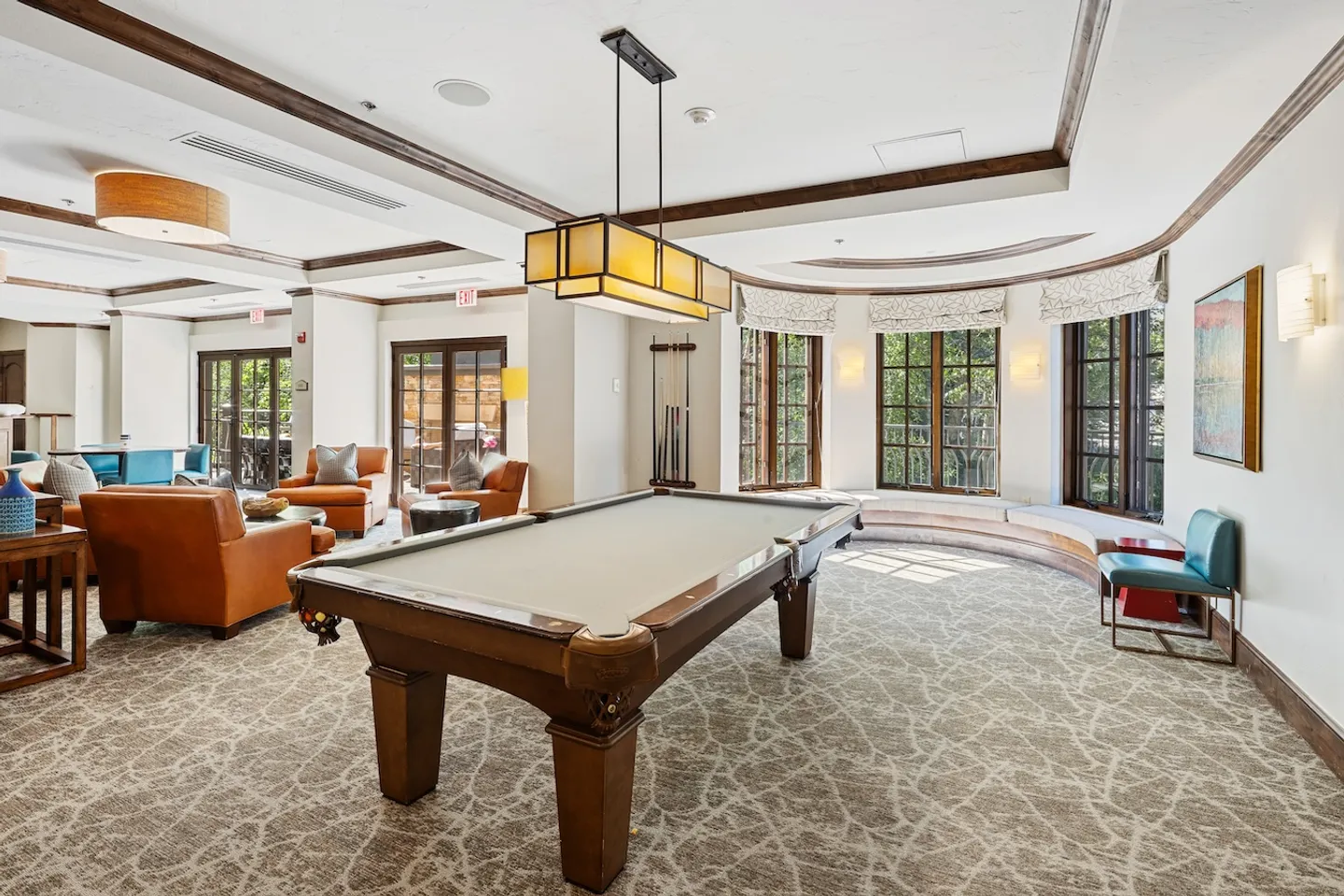 Game room and lounge featuring a billiards table beneath a rectangular pendant light, patterned carpet, and curved window seating.