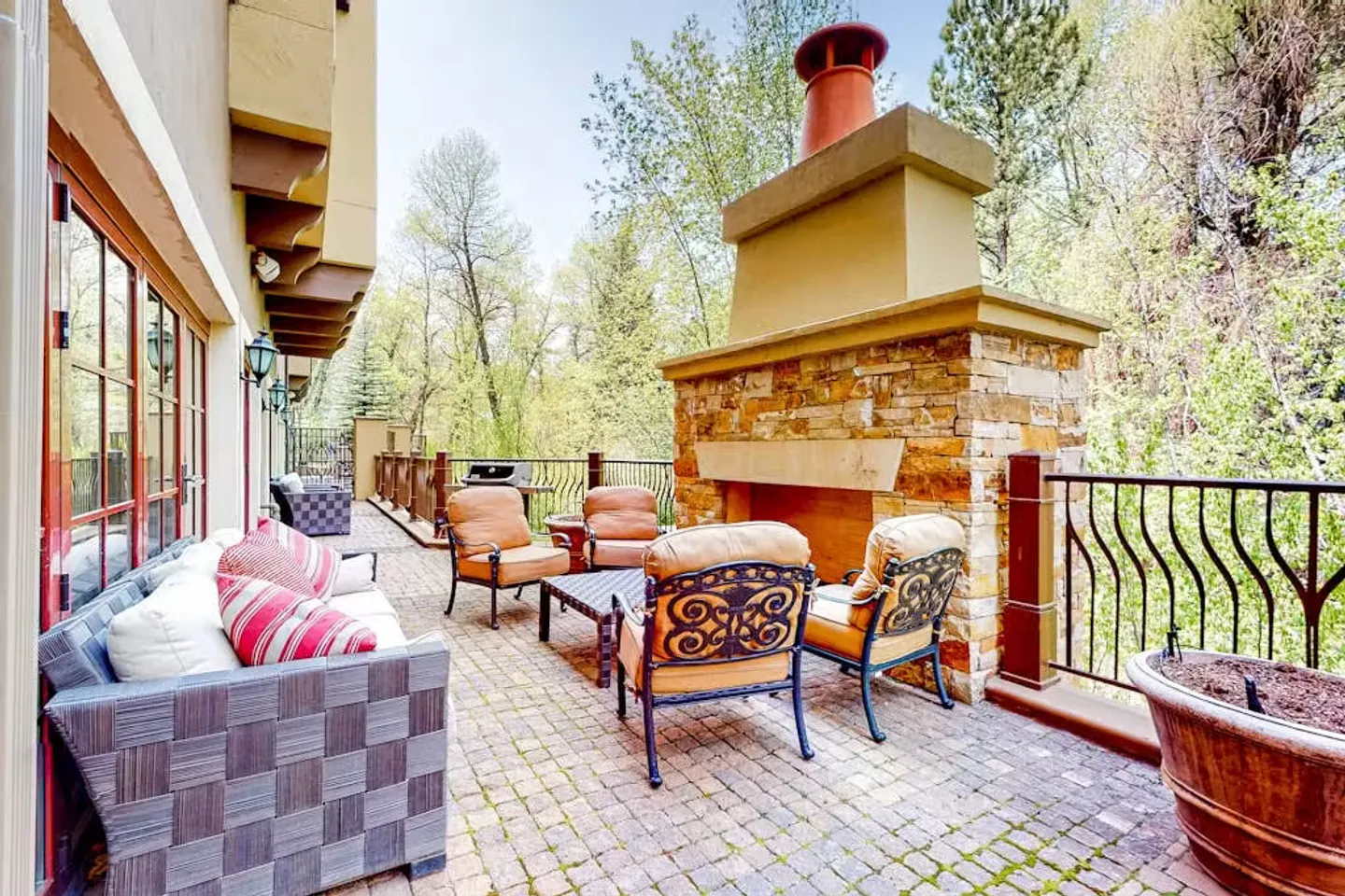 Outdoor patio with a stone outdoor fireplace, paved flooring, patio chairs, a coffee table, and an outdoor sofa.