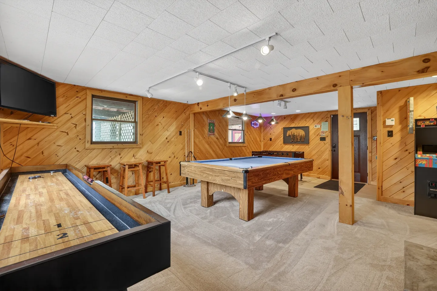 Game room featuring knotty pine wood walls, carpeted floors, a pool table, and a shuffleboard table.