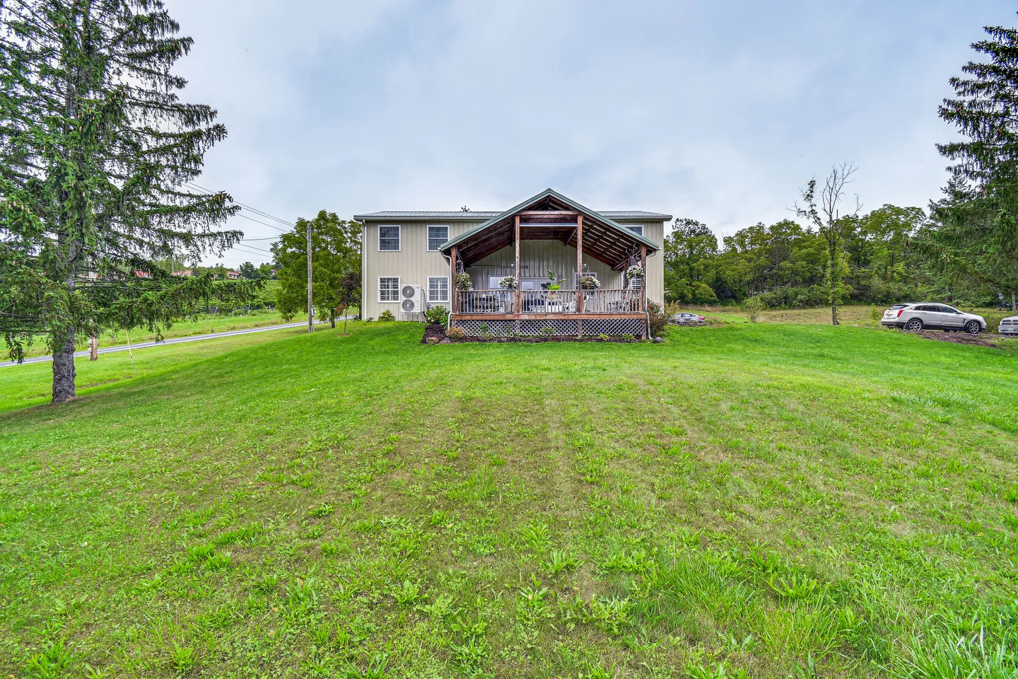 Exterior view of the back of a two-story home featuring a covered back porch and an expansive green grass lawn.