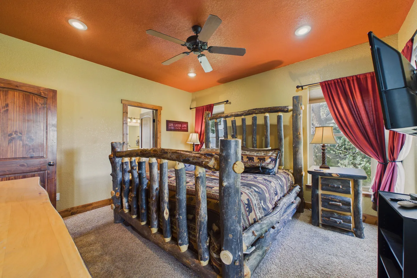 Bedroom featuring a log-style bed frame, an orange ceiling, matching nightstand, and carpeted flooring.