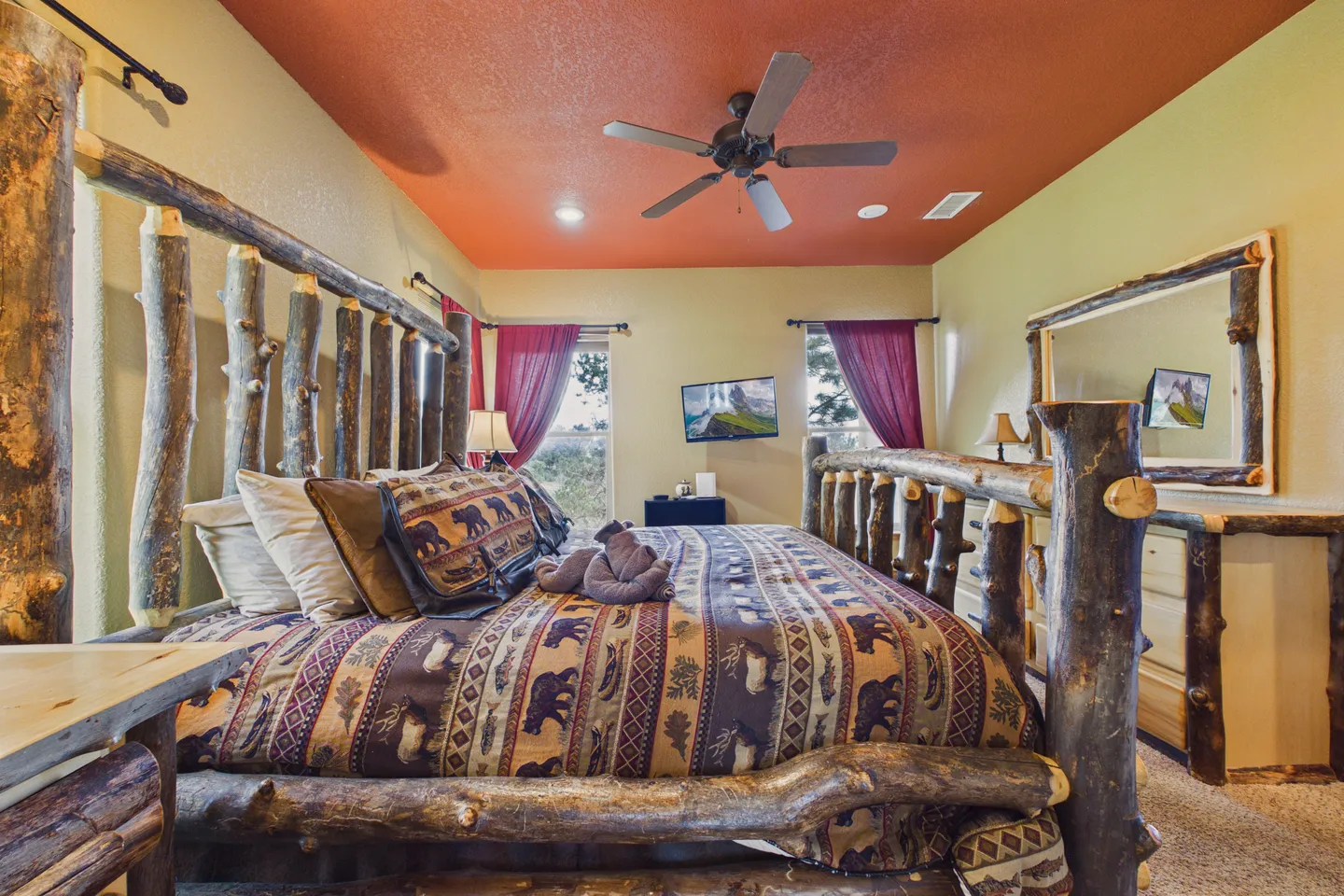 Bedroom featuring a rustic log bed, matching wood dresser and mirror, and an orange ceiling.