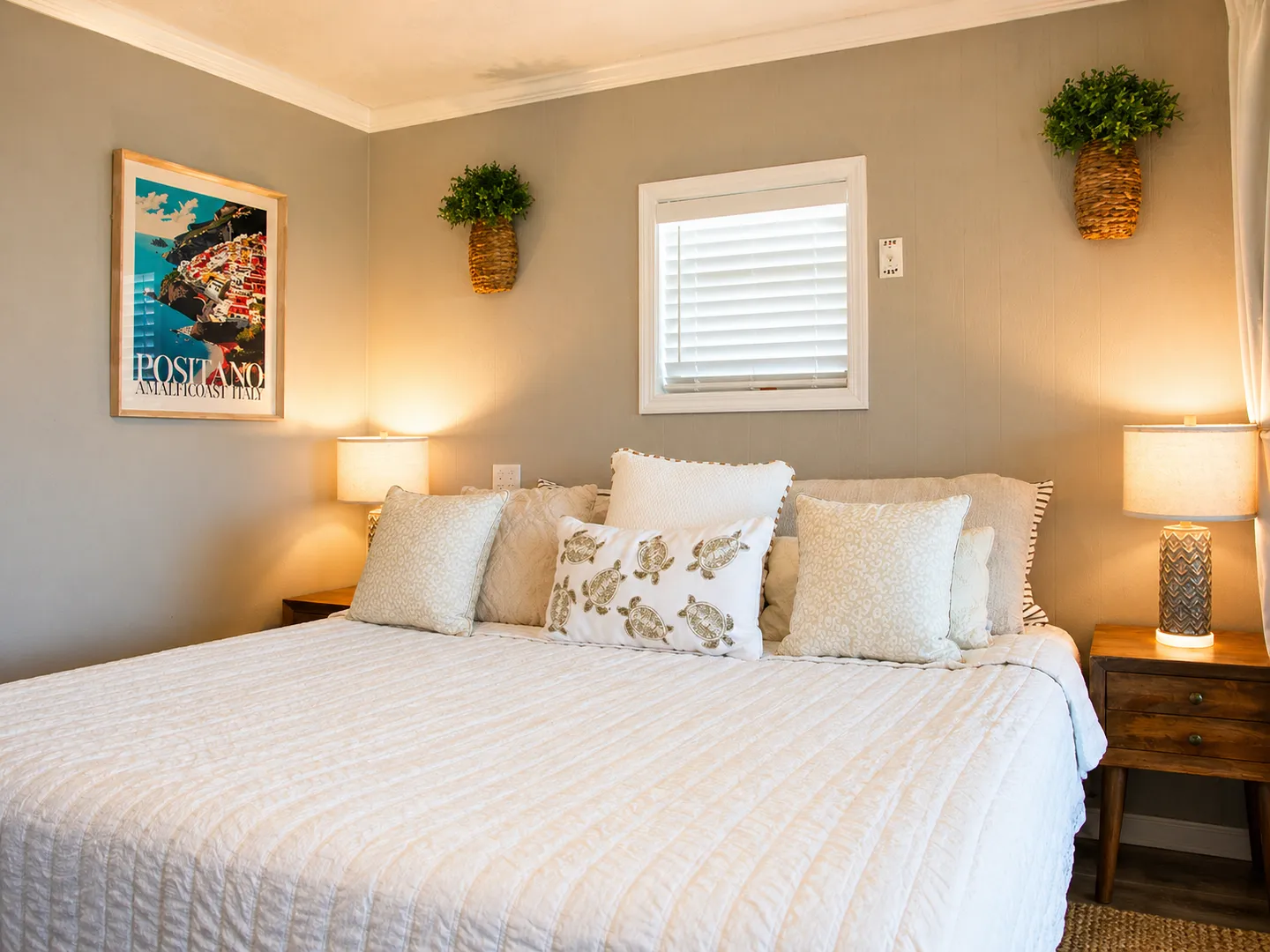 Bedroom with a neatly made bed, decorative pillows, bedside tables with lamps, and wall art.