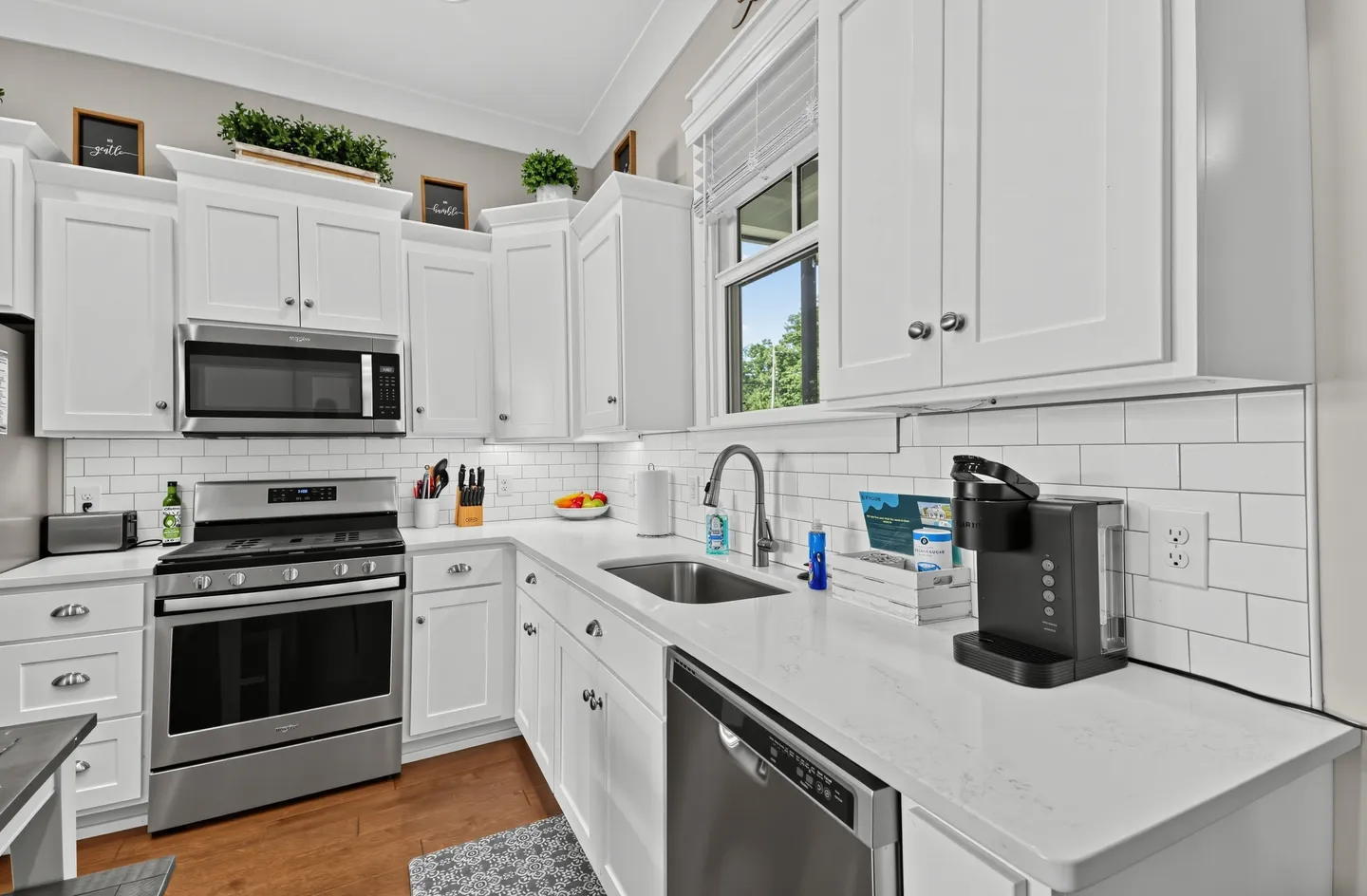 A kitchen with white shaker cabinets, light countertops, subway tile backsplash, and stainless steel appliances.