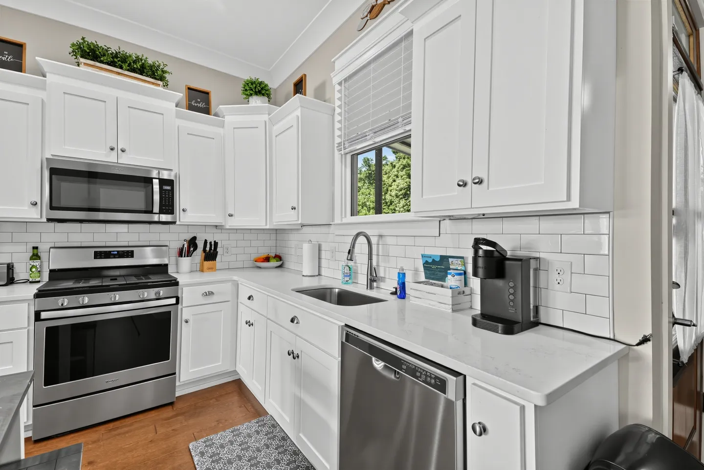 Kitchen with white shaker cabinets, white subway tile backsplash, light countertops, and stainless steel appliances.