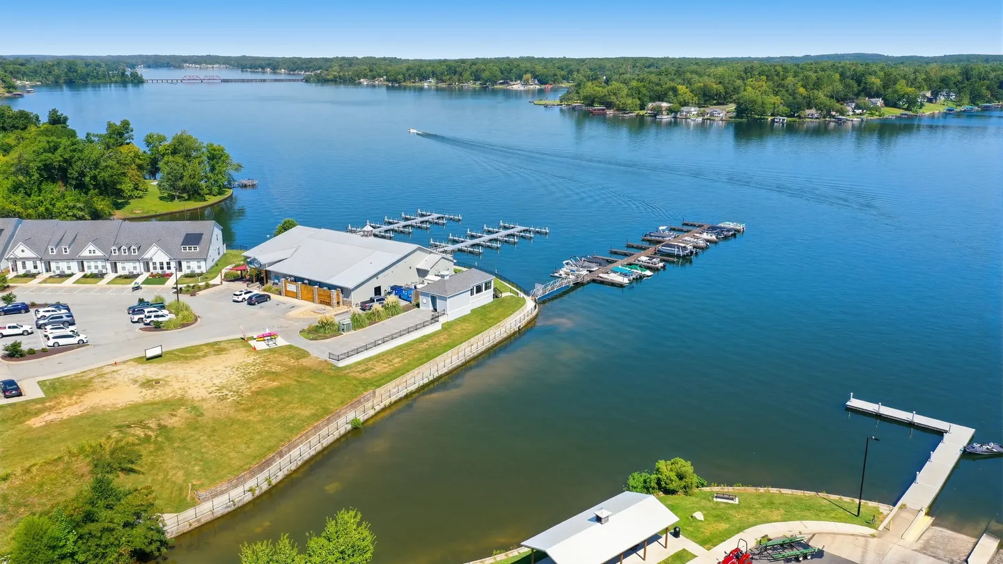 Aerial view of a lakefront community with boat docks, marina buildings, and a wide blue lake.