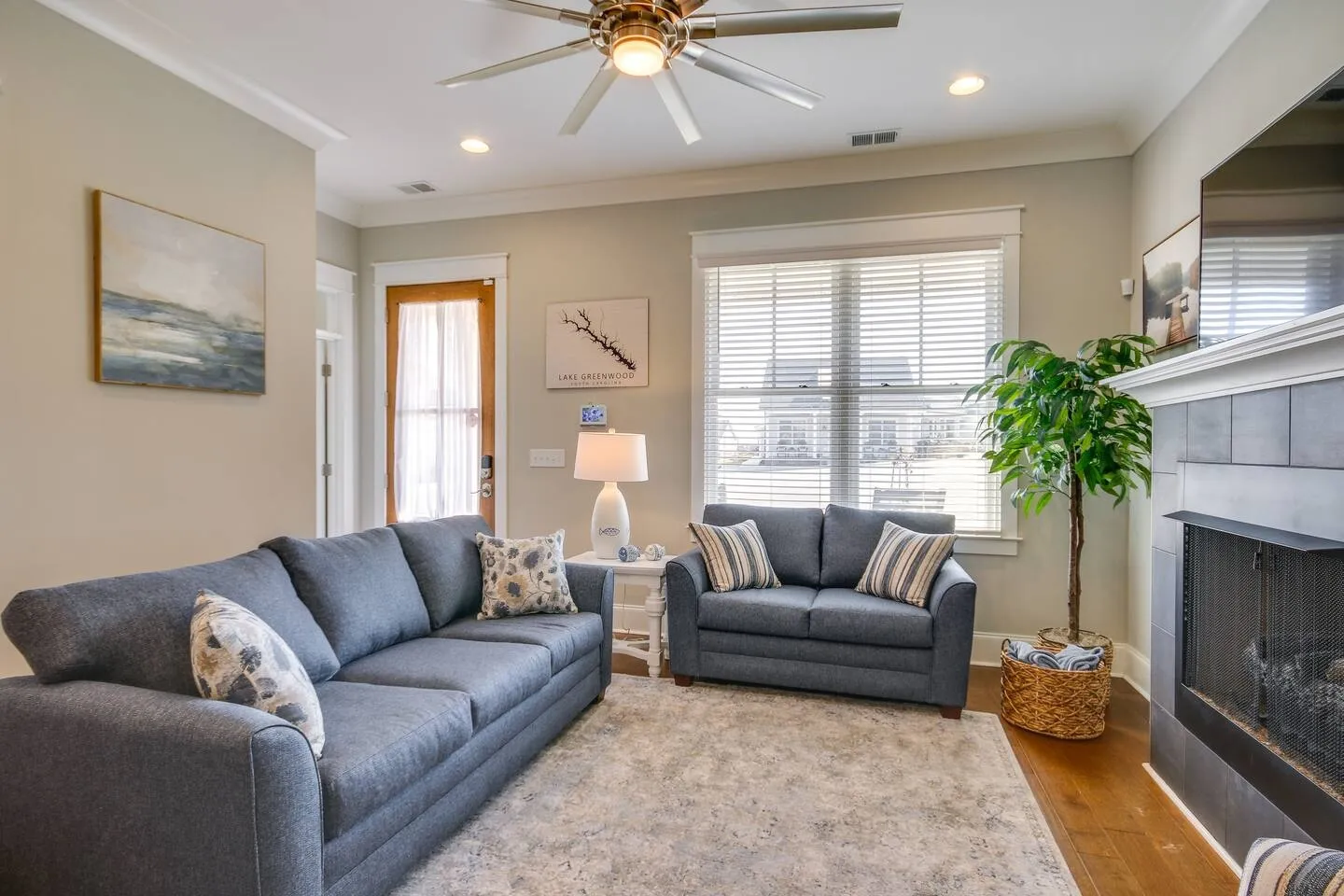 Living room with blue upholstered sofa and loveseat, an area rug, a fireplace, and a window with blinds.