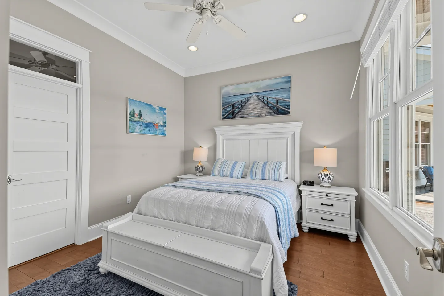 Bedroom with a white panel bed, matching nightstands, a storage bench, and wood flooring.