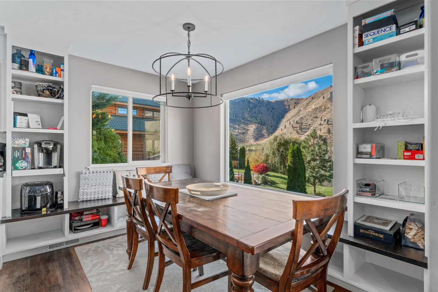 Dining area with a wooden table, built-in shelving, and large picture windows looking out at hills.