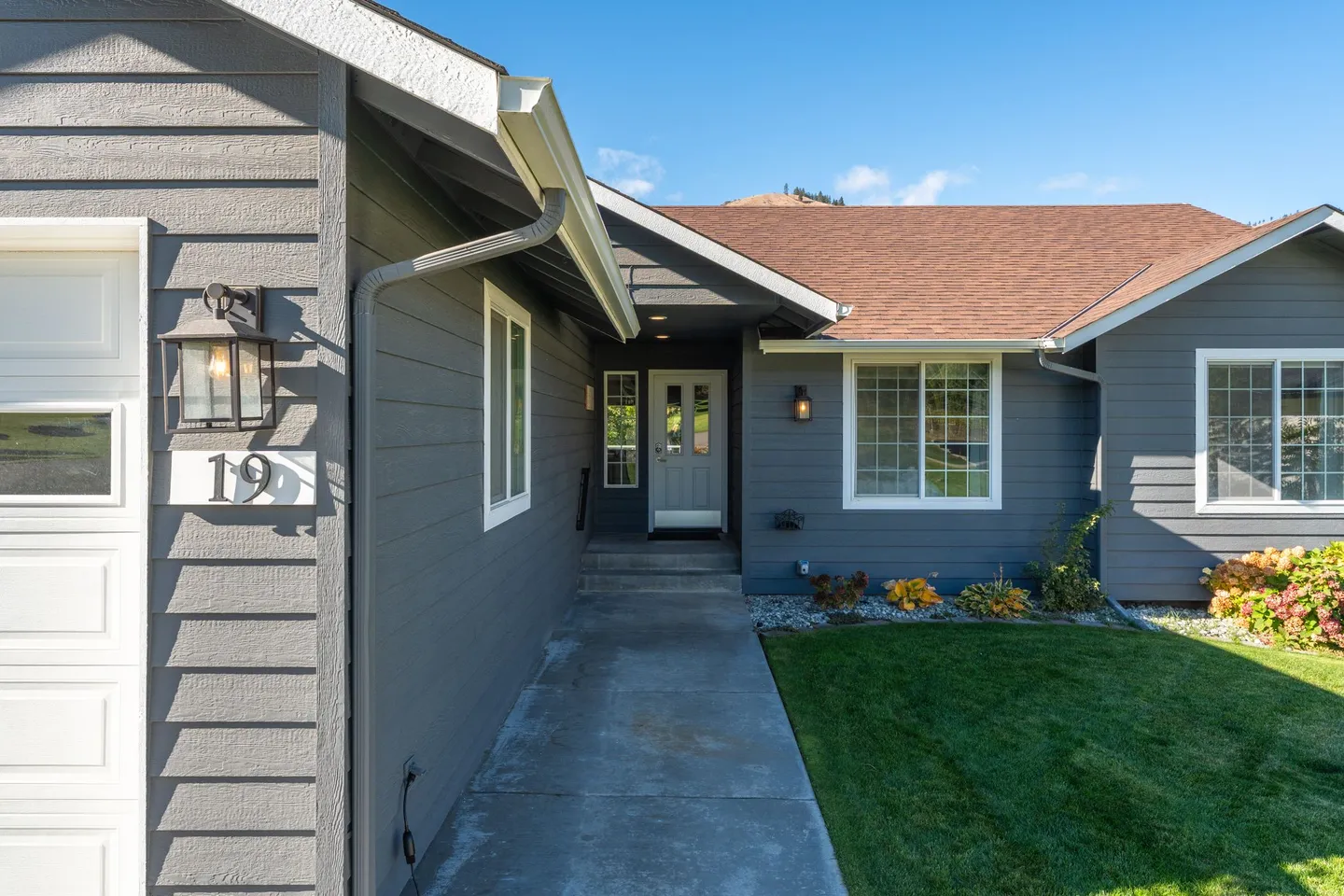 Front walkway leading to the recessed covered entrance of a gray home with white trim.
