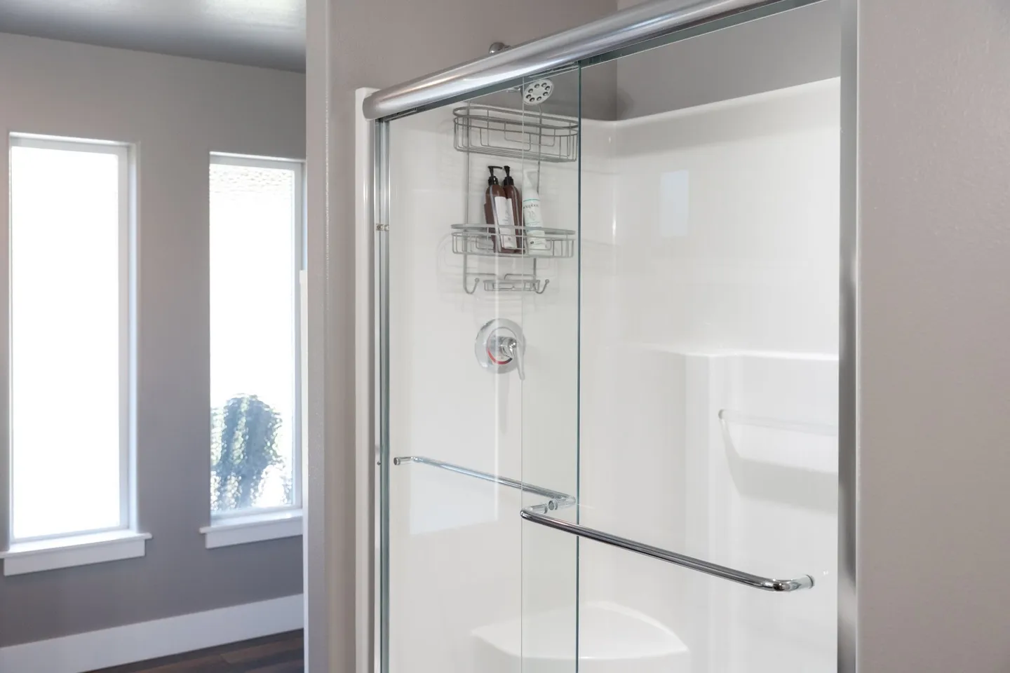 Bathroom shower with sliding glass doors, white surround, and chrome fixtures.