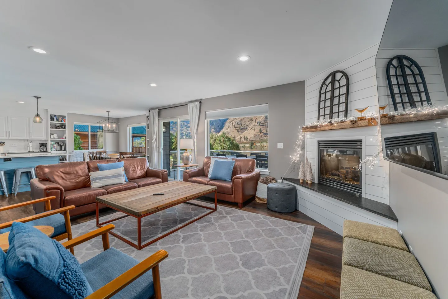 Open-concept living room with leather couches, a fireplace, and large windows showing scenic mountain views.