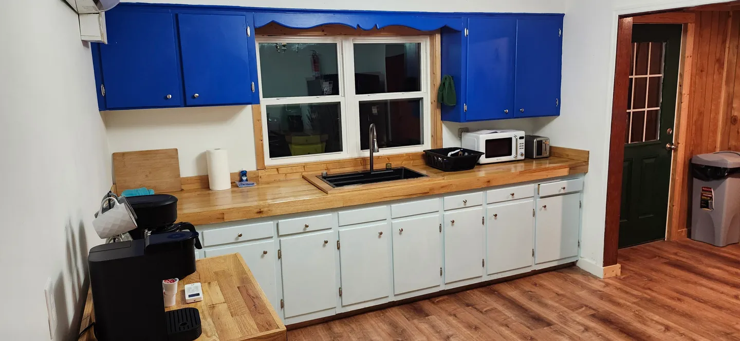 Kitchen featuring light blue lower cabinets, bright blue upper cabinets, a wooden countertop with a sink, and wood-look flooring.