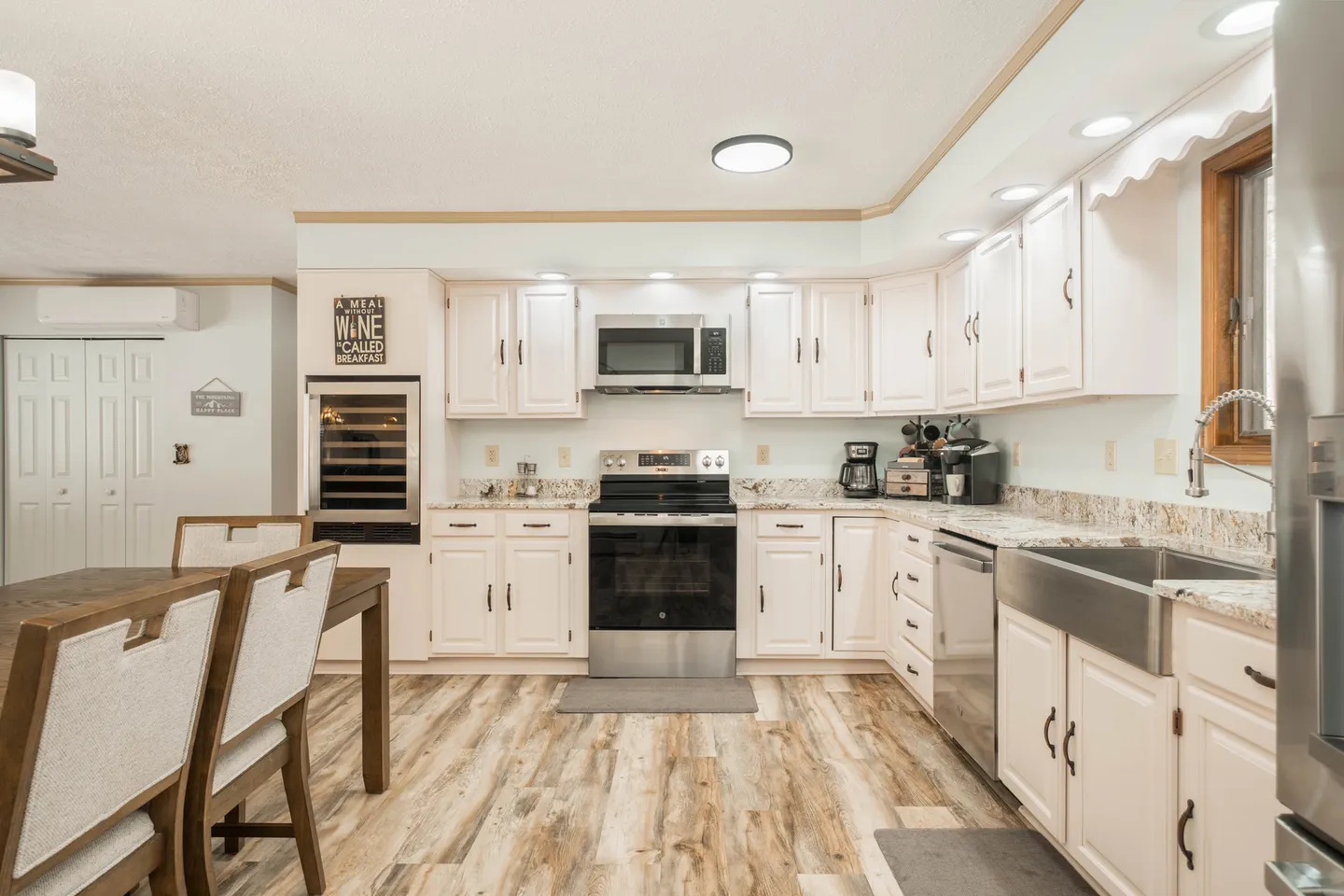 Kitchen with white cabinetry, stainless steel appliances, speckled countertops, and an adjacent dining table.