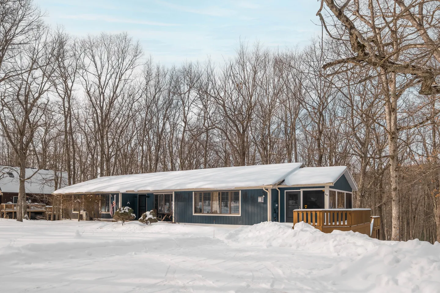 Exterior view of a single-story blue house surrounded by bare trees and snow-covered ground.