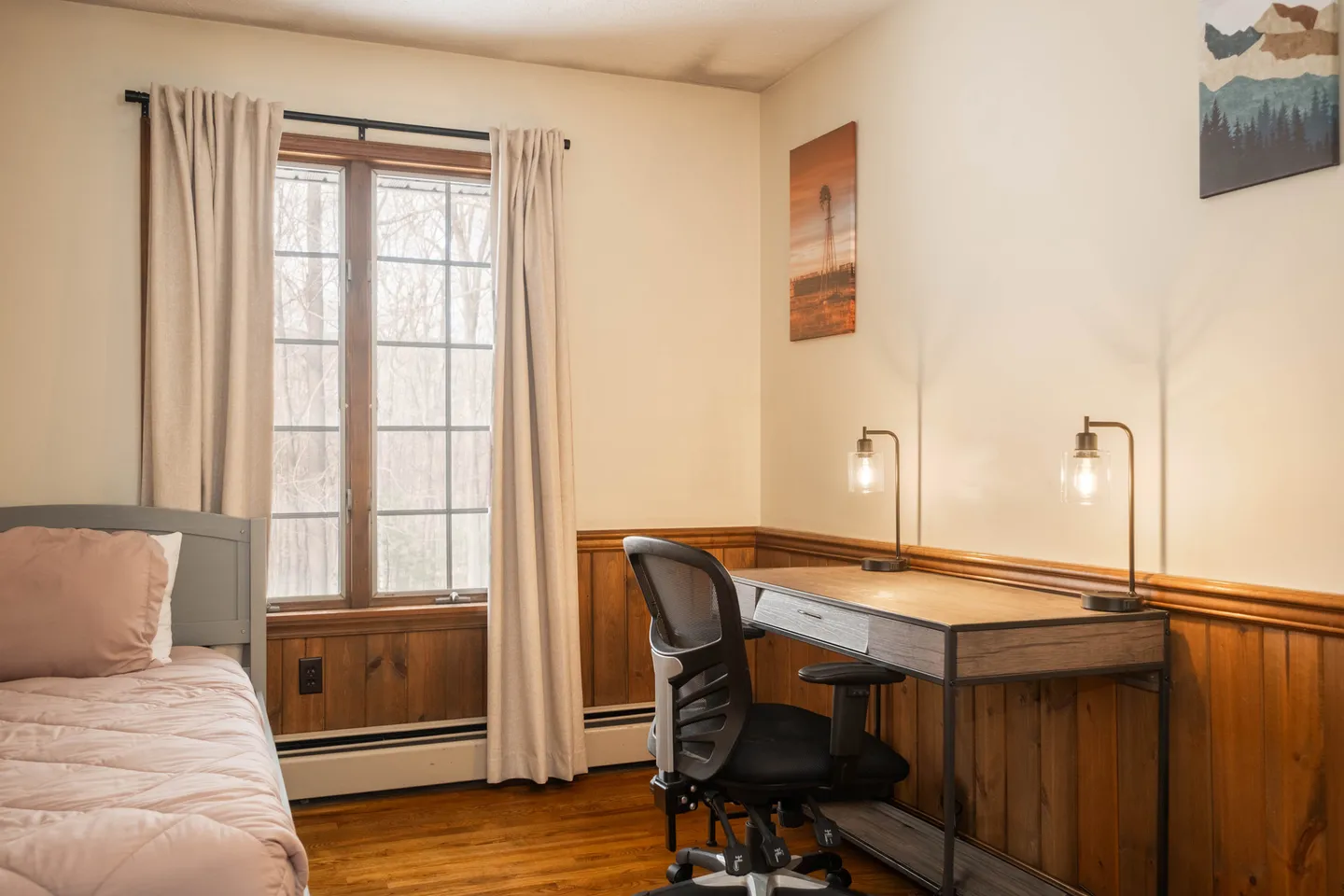 Bedroom featuring a wooden work desk with an office chair alongside a single bed and a large window.