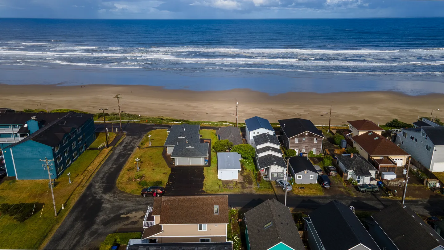 Aerial view of a coastal neighborhood situated directly along a sandy beach and the ocean.