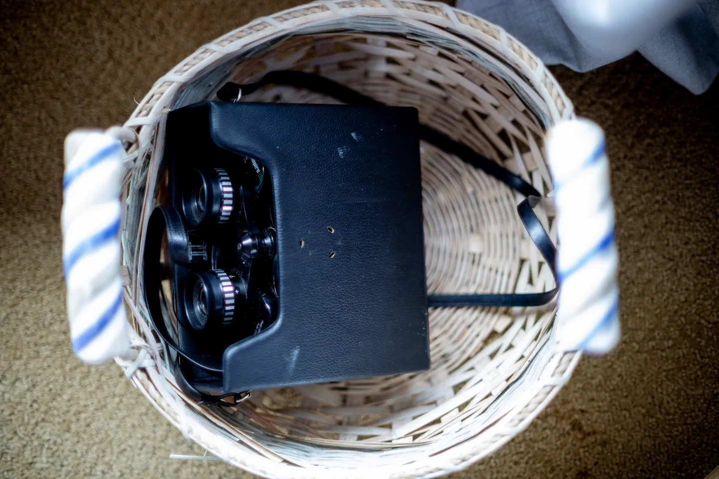 A pair of binoculars in a black carrying case resting inside a woven basket.
