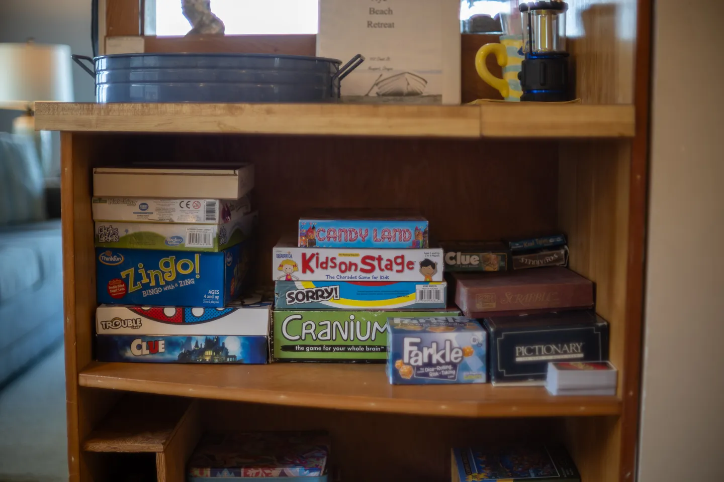 Wooden shelf stocked with a variety of board games and card games.