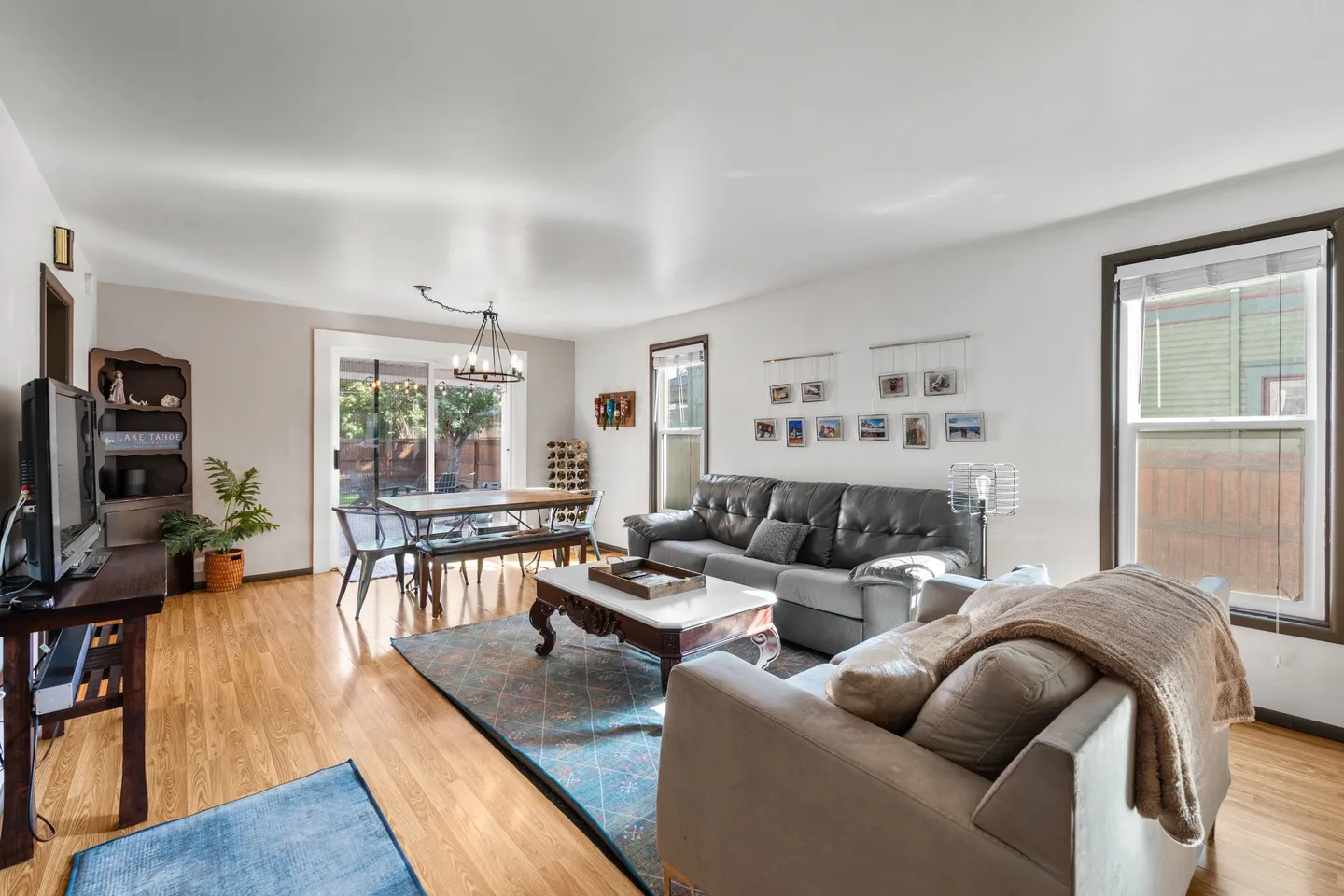 Open living and dining area with hardwood floors, comfortable seating, a television, and a dining table by sliding glass patio doors.