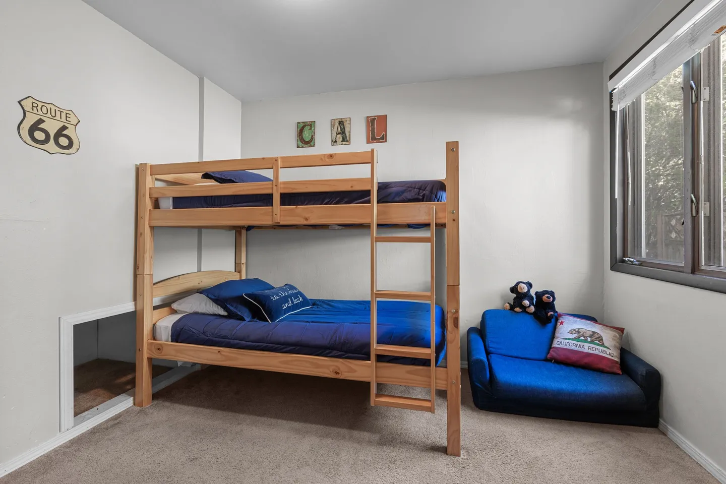 Bedroom featuring a wooden bunk bed with blue bedding, a small blue fold-out chair, and carpeted flooring.