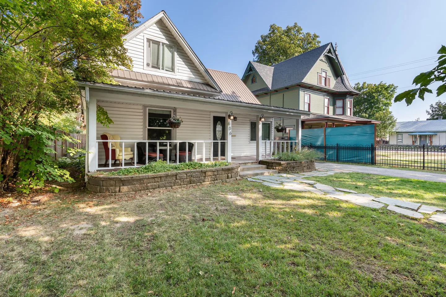 Exterior front view of a two-story home with white siding, a covered front porch, and a grassy front yard with stone pavers.