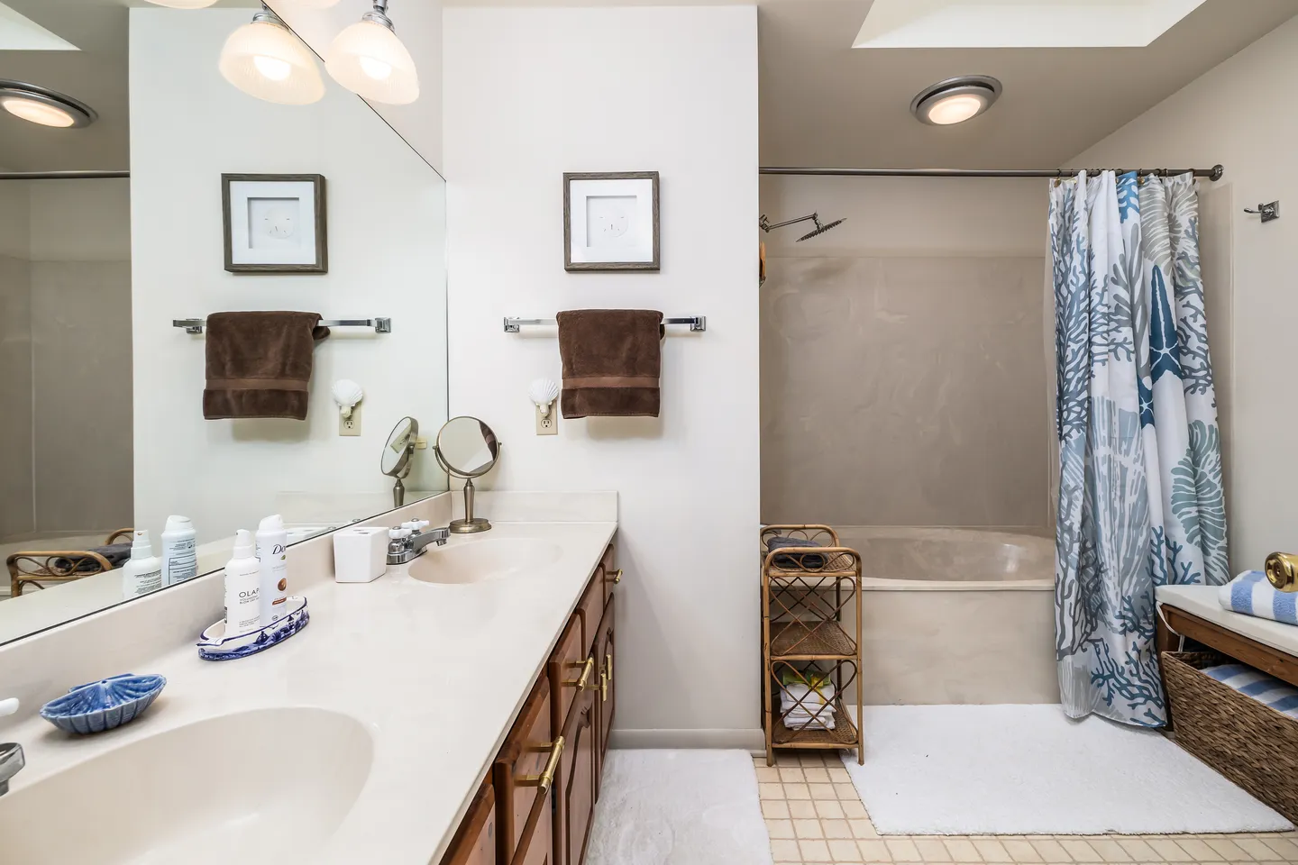 Bathroom with double vanity, large mirror, and a combination bathtub and shower with a printed curtain.
